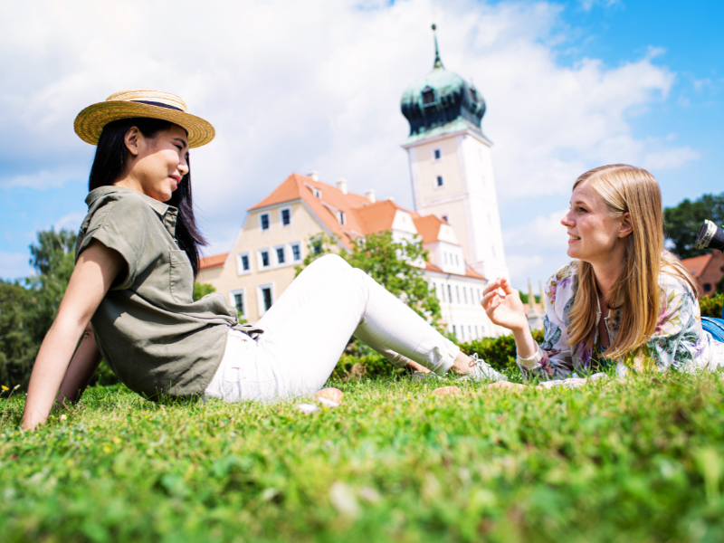 Zwei Freundinnen auf einer Wiese vor dem Barockschloss Delitzsch